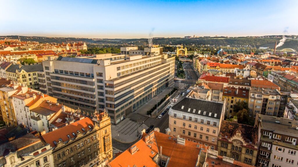 Aerial view of a city with a large modern office building surrounded by red-tiled rooftops in the historic downtown area.